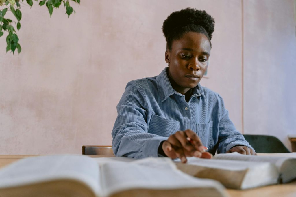 Focused woman reading and studying a Bible at a table indoors.