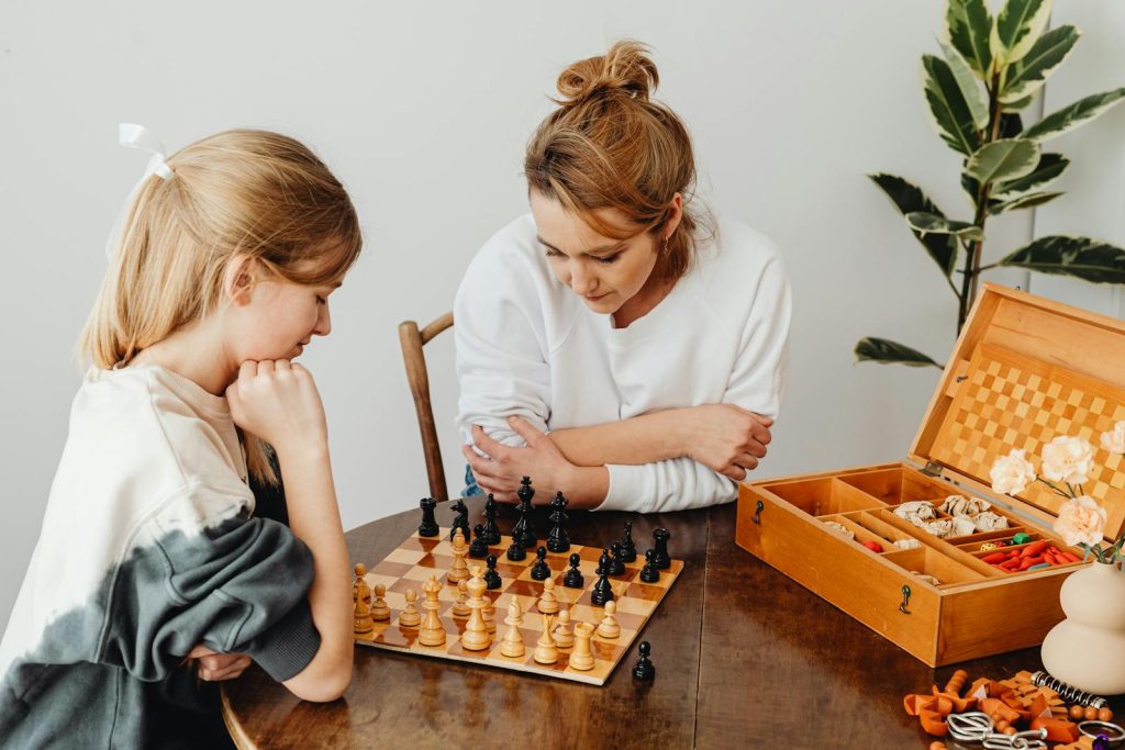 A mother and daughter engage in a thoughtful game of chess at home, fostering bonding and strategic thinking.