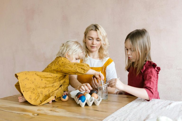 Mother and children enjoy Easter egg decorating together at home, fostering creativity and bonding.