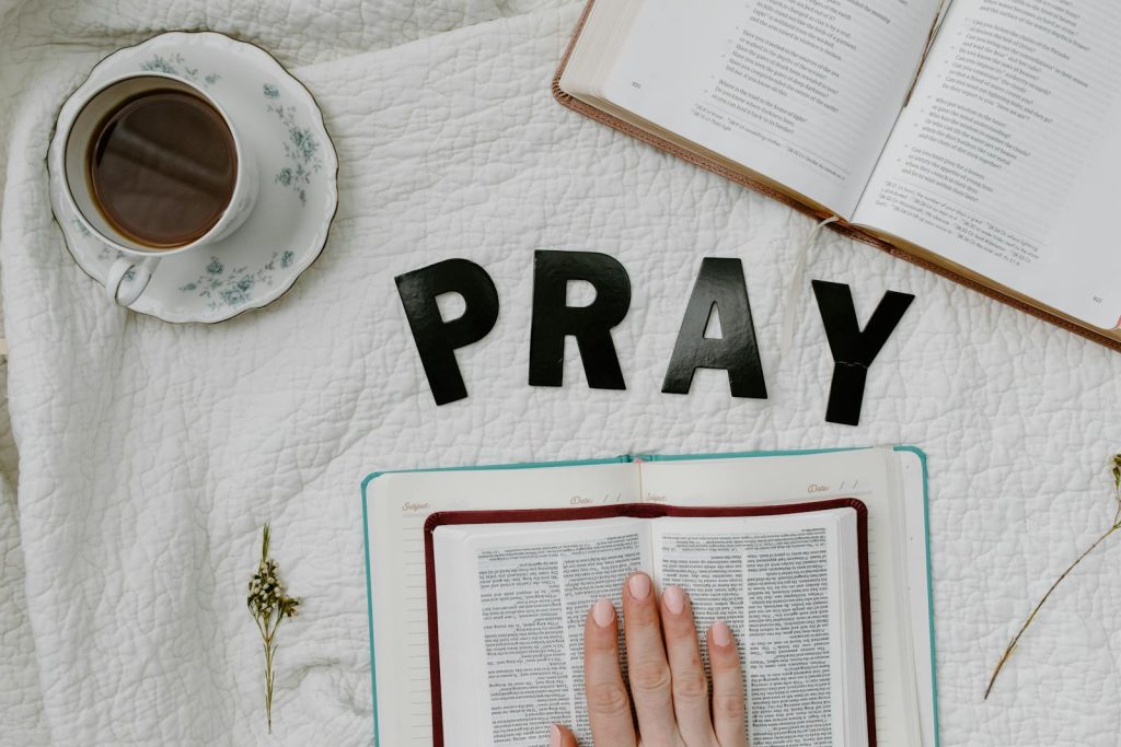 Flat lay of morning prayer routine including Bible, coffee, and 'PRAY' letters.